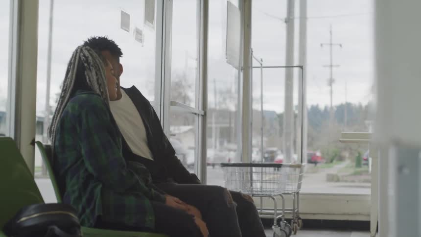 Black man and woman sit and talk indoors on a cloudy day