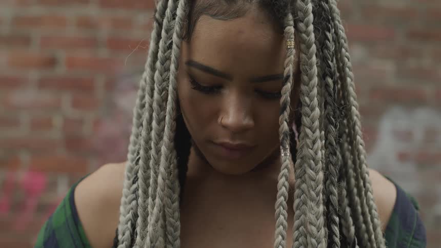A young black woman standing in an alleyway
