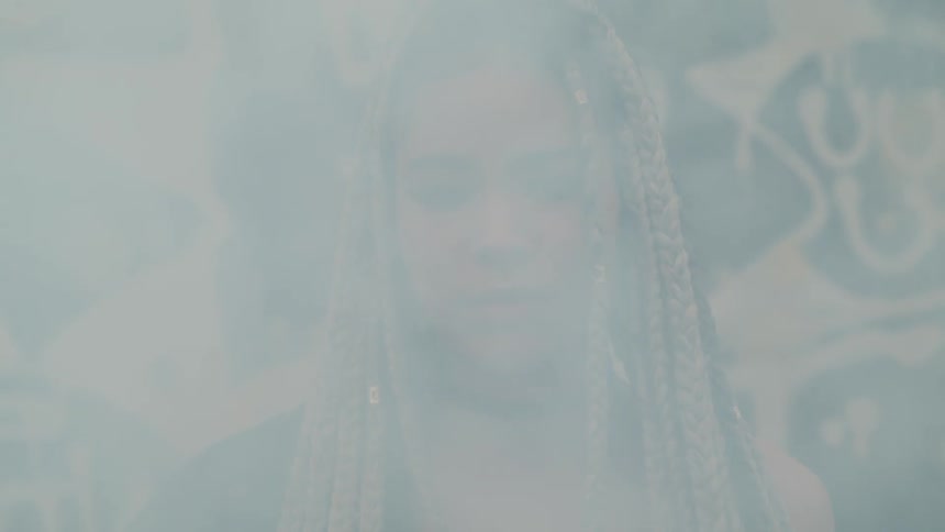 A woman is standing as smoke covers her