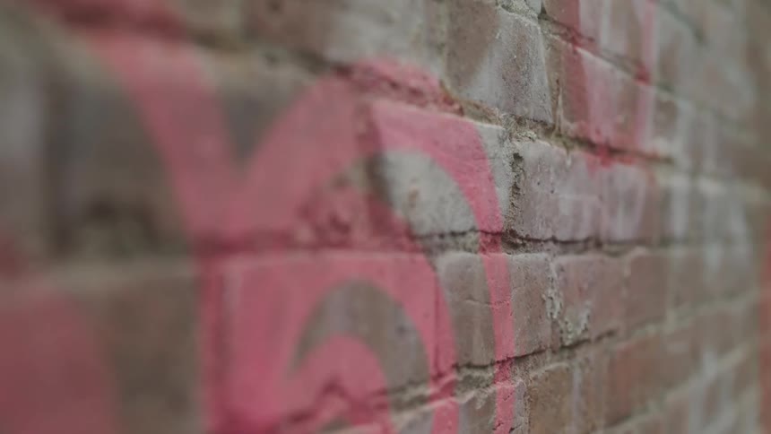 Red graffiti covers a brick wall