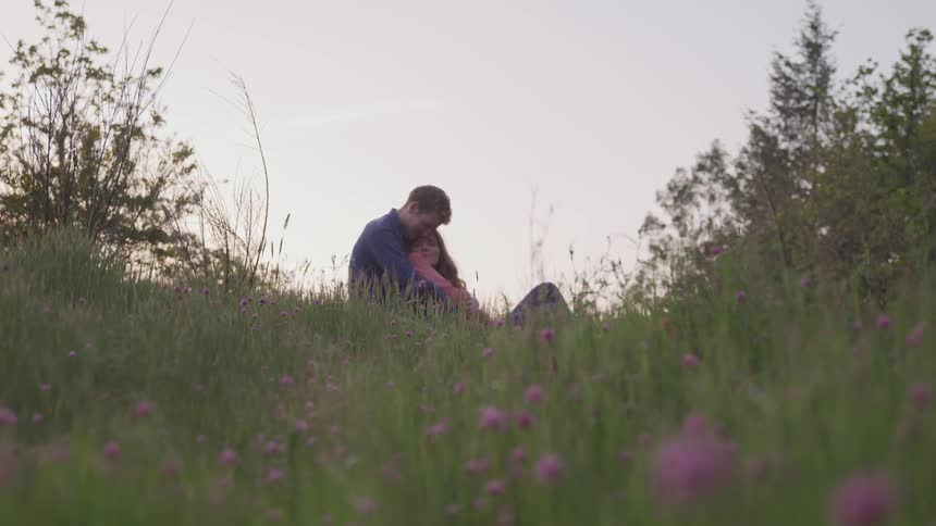 A couple holds one another in the grass