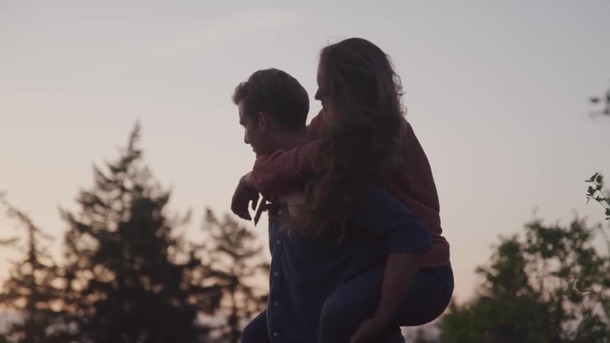 Man piggy backing his couple on the park at the sunset