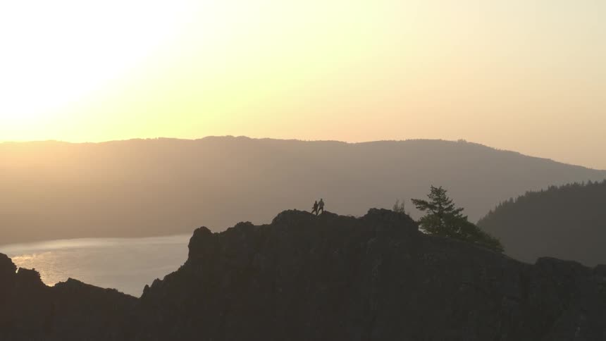 A man and woman stand at the top of a mountain