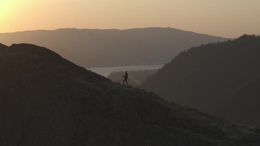 A person is hiking up a trail and stops to admire the view