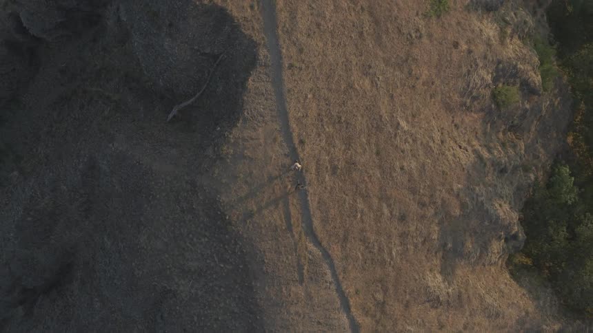An aerial view of two people walking on a remote dirt path