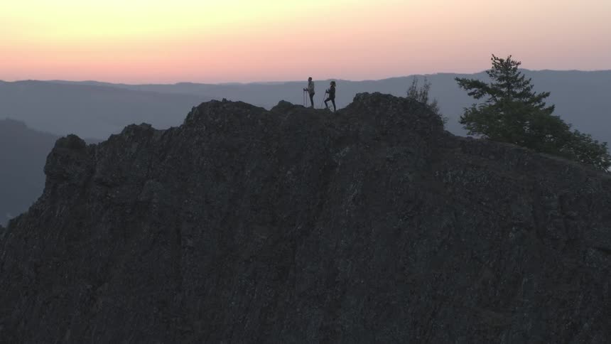 Two hikers stand on crest of ridge overlooking river