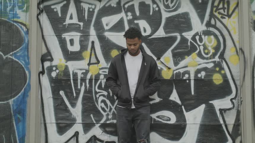 A man standing next to a wall covered in graffiti