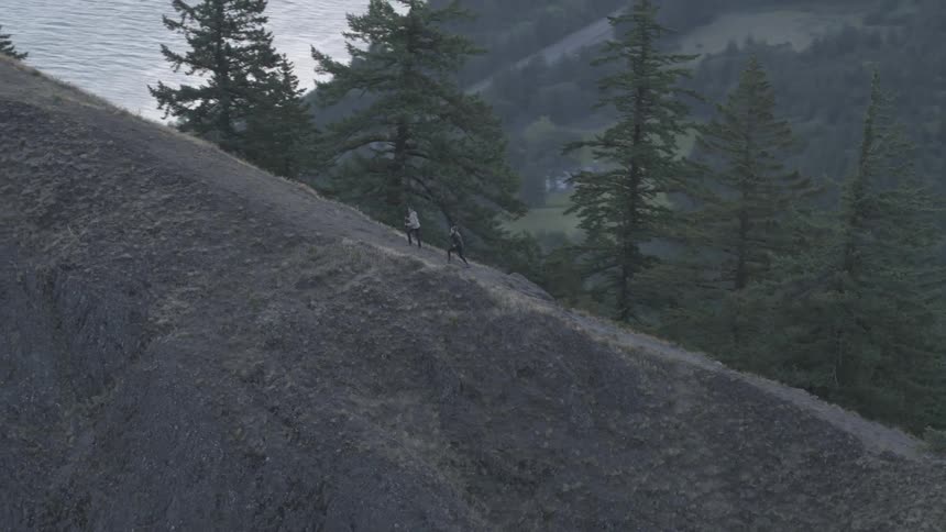 Two people climb a tall mountain pathway