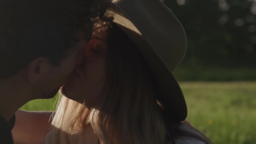 Couple stand in meadow staring into each others eyes then kiss
