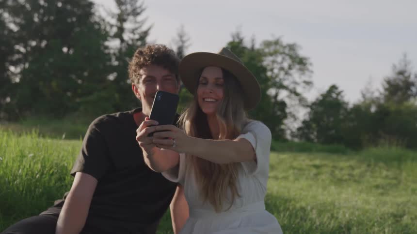 Couple taking a selfie sitting on grass outdoors