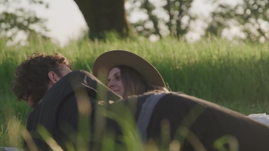 A man and woman lay in the grass and cuddle
