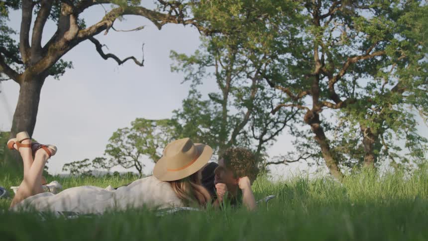 A woman and man lay together in tall grass
