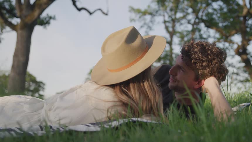 A man and a woman kiss while lying in the grass
