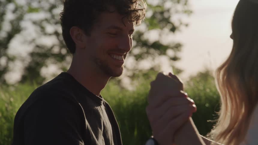 A man laughs as he stands in front of a woman in a rural area