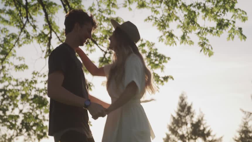 A man and a woman skip and dance through a grassy field