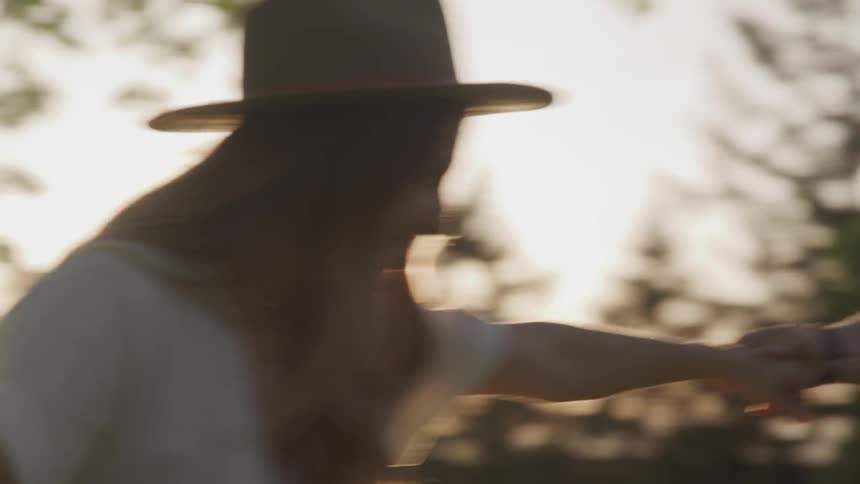 A man and woman hold hands and spin before kissing