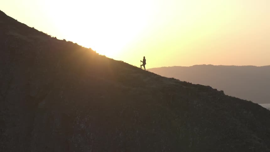 A hiker standing on a mountain slope at sunrise