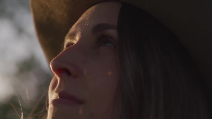 A young woman wearing a hat looks up at the sky