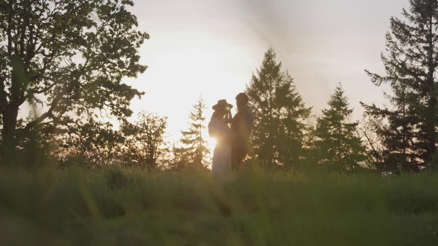 Couple stand holding each other in field