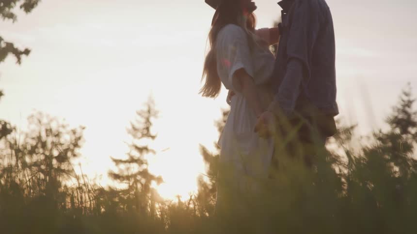 A couple dances in tall grass outdoors