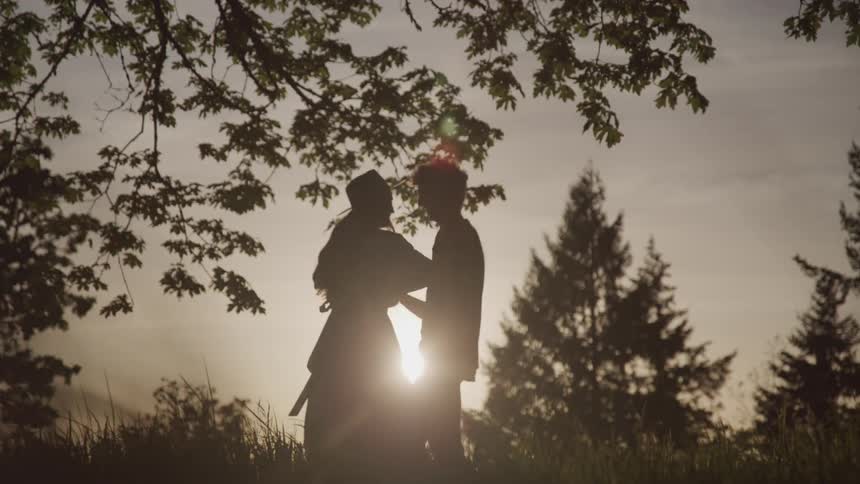 A man and a woman hold hands and dance in a field