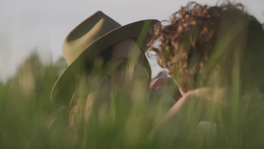 A woman and man are laying in the grass and talking