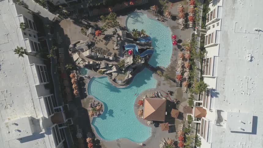 A large swimming pool that sits between three hotel buildings
