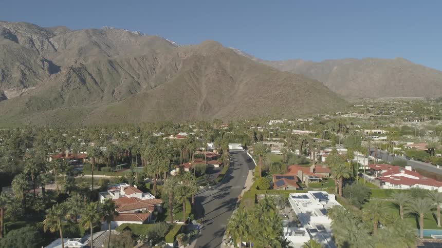 An aerial view of a neighborhood by mountains is displayed