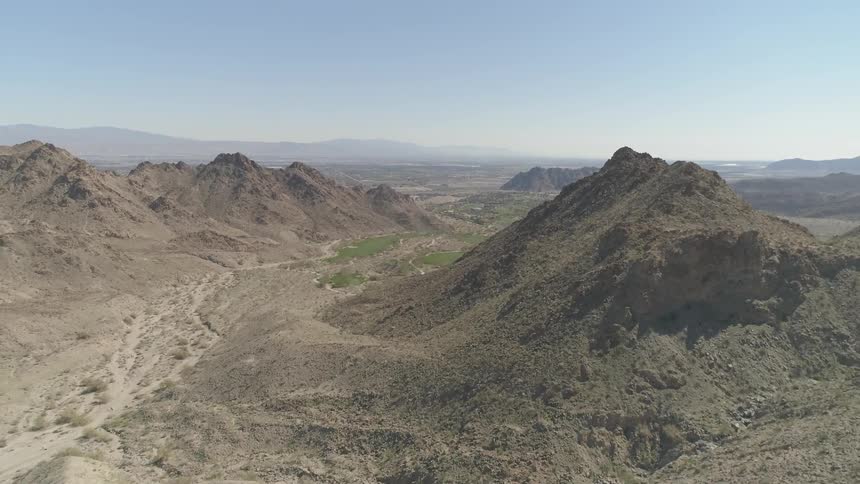 A valley between sets of craggy mountain ridges in the desert