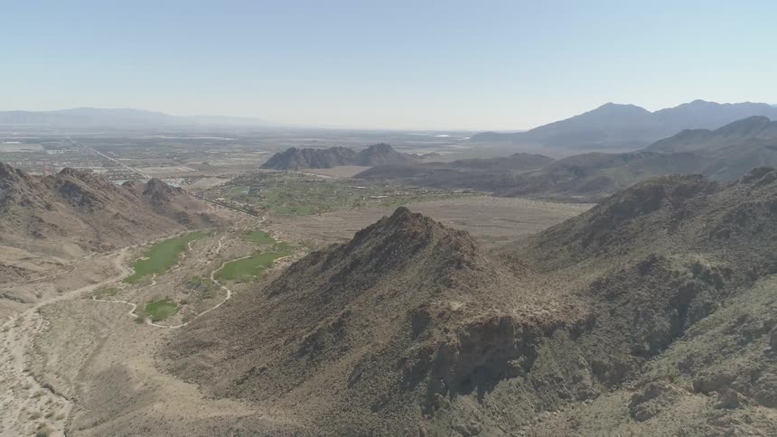 A valley with a dry riverbed and a small amount of grass is nestled between the hills