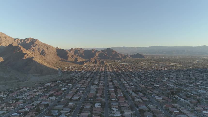 Sunlight partially lights rows of houses near mountain range