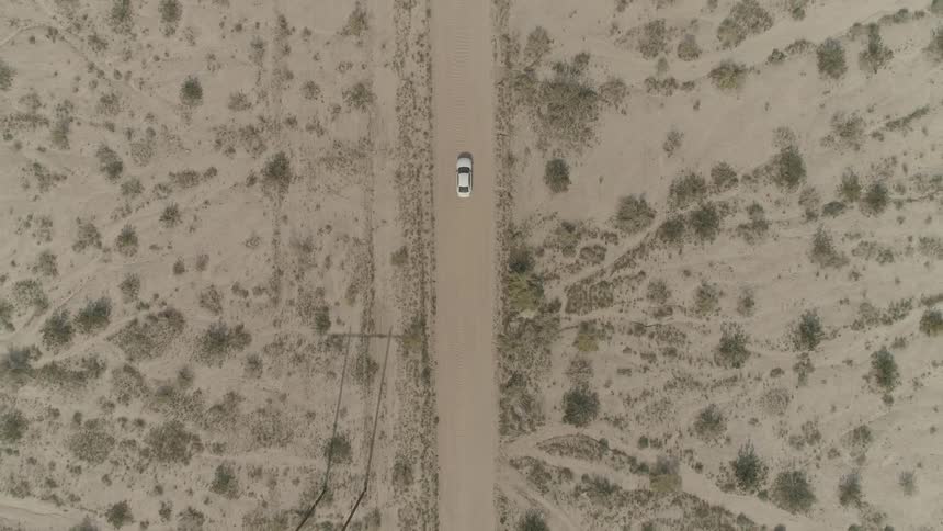 Birds eye view of a car driving down a dirt road
