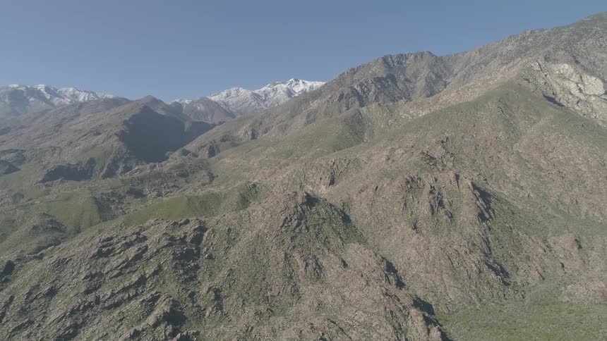 Valley borders mountain range with snow capped mountains on horizon