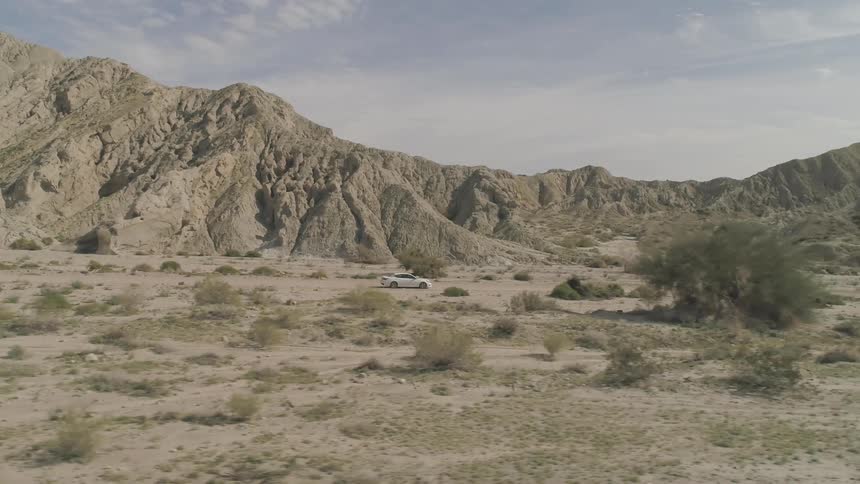 A white car traveling through the desert