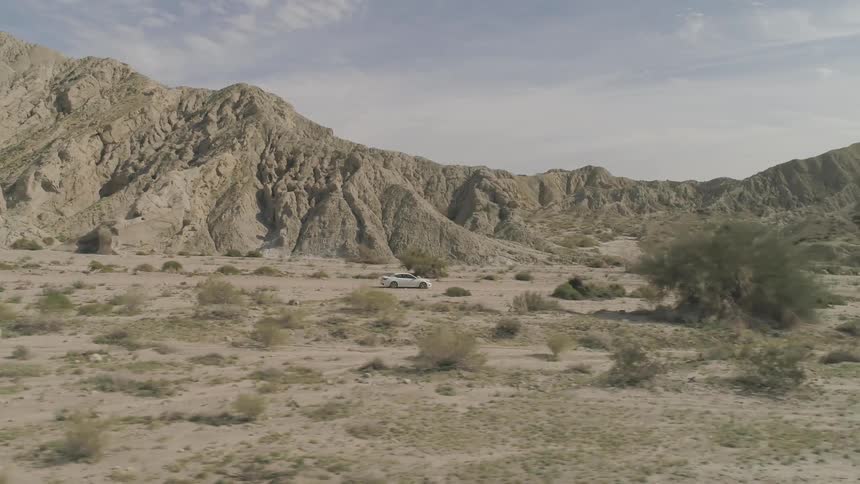A white sedan driving on the desert at the mid day