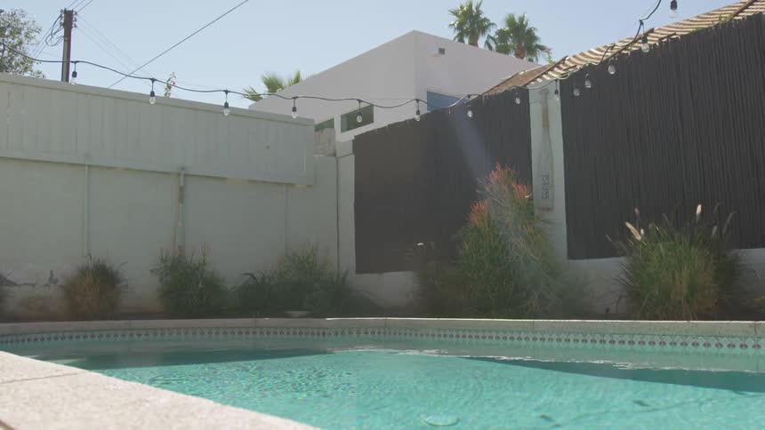 A swimming pool in the gated back yard of a building