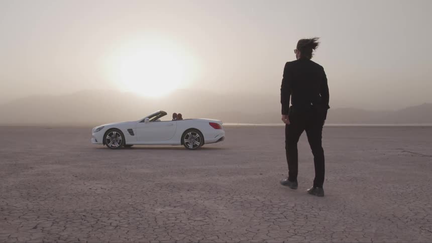 A man is walking to his car in a desert area