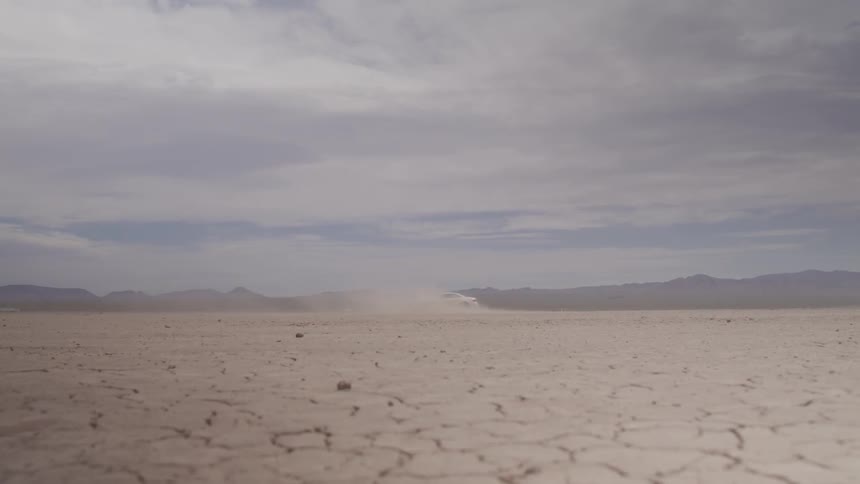 White car drives erratically in the desert