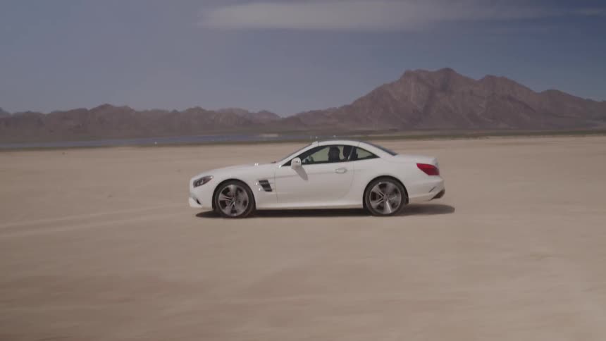 A white car drives very fast across an open area