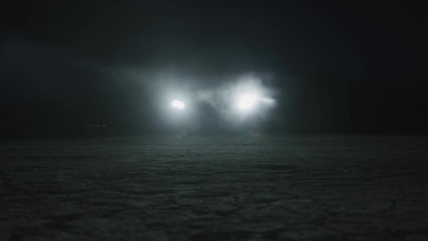A car headlights in the dark with smoke coming off of it