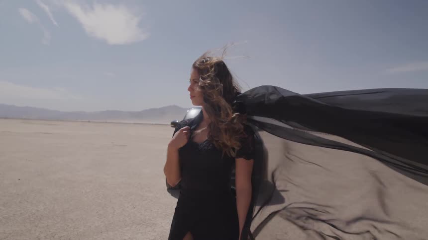 A woman is standing outdoors in a desert area