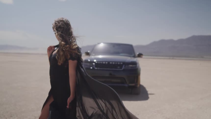 A woman stands in front of a car