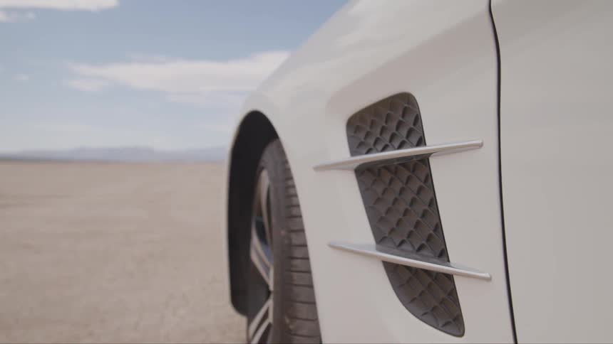 A white car in the middle of a flat sun baked desert