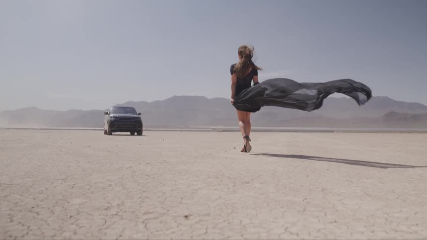 A woman in a black dress is walking towards a vehicle