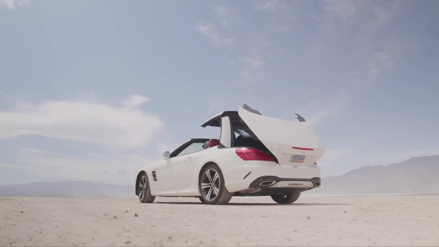 The roof opens on a white convertible parked in the desert