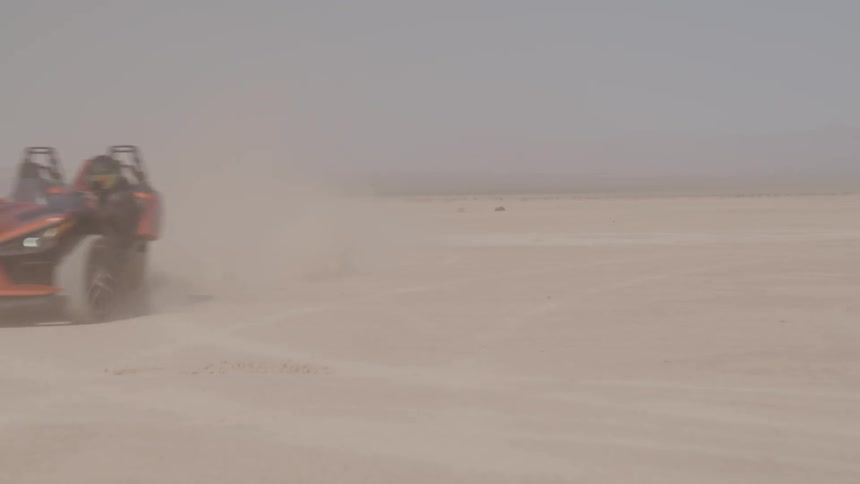Open top sports car is moving through the desert on a high speed