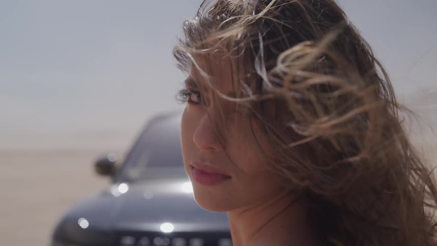 A woman stands in front of a range rover