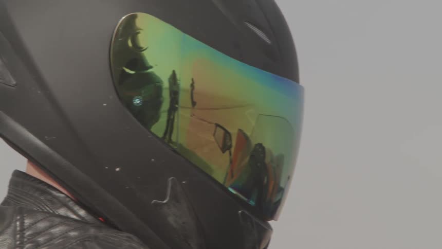 A man sits in a car in a helmet
