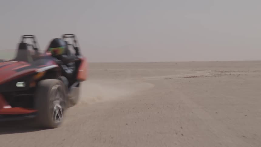 A person drives a dune buggy through the desert sand