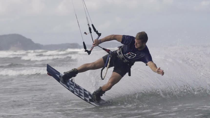 Man windsurfing across the water on a sailboard on a windy day.